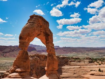 Delicate arch on landscape against cloudy sky