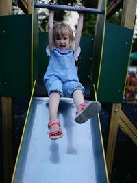 Cute girl playing on slide on playground