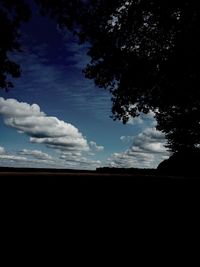 Silhouette trees against cloudy sky