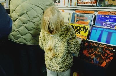 Rear view of girl with blond hair standing in market