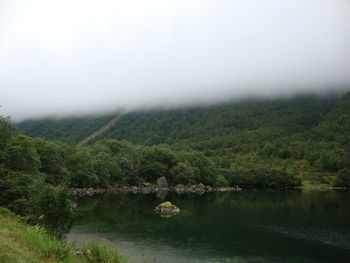 Scenic view of lake by trees against sky