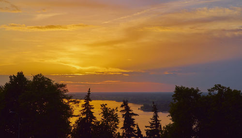 Silhouette trees by sea against romantic sky at sunset