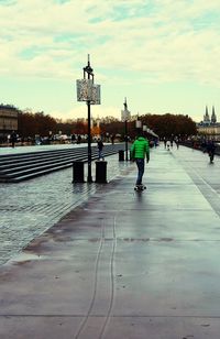 Rear view of woman walking in city against sky