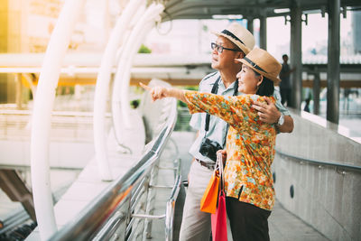 Woman holding bicycle while standing on railing