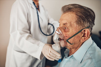 Doctor applying a medicine during inhalation to senior man suffering from lung disease