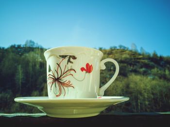 Close-up of coffee cup against blue sky