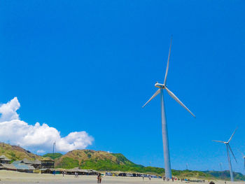 Low angle view of wind turbine against blue sky