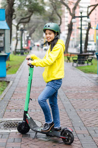 Full length of young woman with push scooter