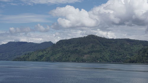 Scenic view of sea by mountains against sky