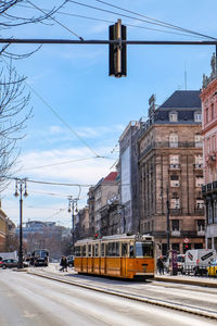 Tramway on street by buildings against sky