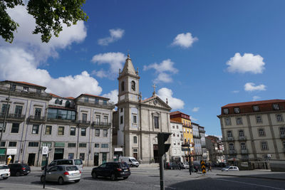 Cars on road by buildings against sky in city