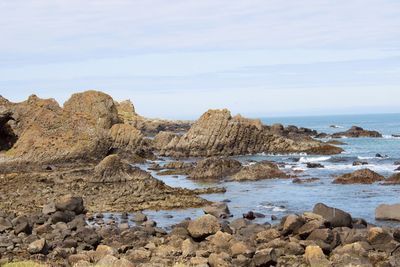 Rocks on sea shore against sky