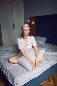 Woman in pajamas and with a sleep mask on the bed in the bedroom