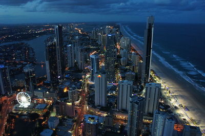 High angle view of city lit up at waterfront