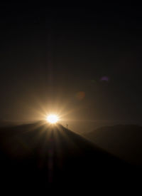 Sun shining through silhouette trees against sky during sunset