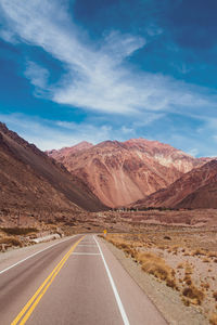 Road leading towards mountains against sky