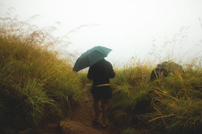 Man holding umbrella against sky during rainy season