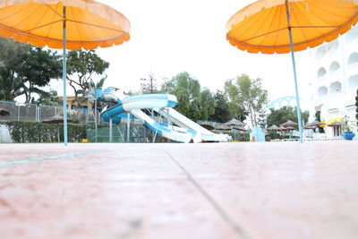 Umbrellas by swimming pool in city against sky