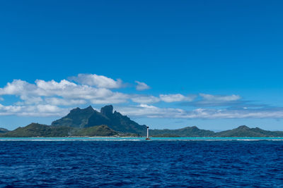 Scenic view of sea and mountains against blue sky