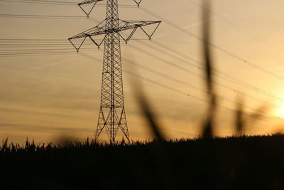 Silhouette electricity pylon against sky during sunset