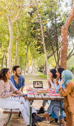 People sitting on table against trees