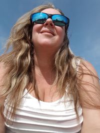 Low angle view of smiling woman wearing sunglasses 