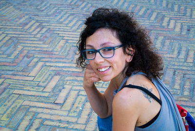 Portrait of smiling woman sitting at footpath 