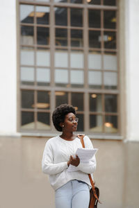 Young man looking away while standing against wall