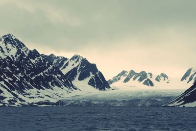 Scenic view of snowcapped mountains by sea against sky