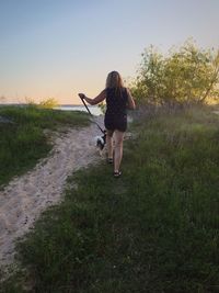 Rear view of woman walking on field against sky