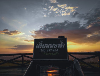 Information sign on road against sky during sunset