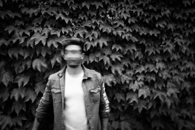 Blurred motion of young man standing against ivy in park