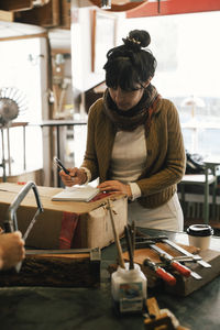 Female customer writing in diary at repair shop