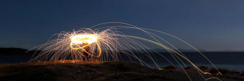 Firework display over sea against sky at night