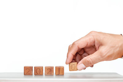 Close-up of hand holding toy against white background