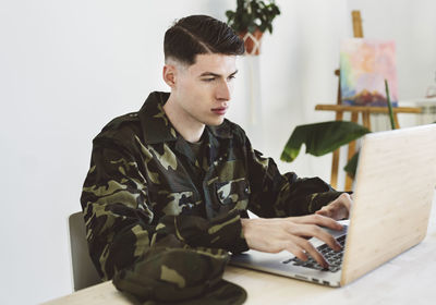 Young army man using laptop at home