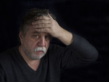 Close-up of tensed mature man against black background