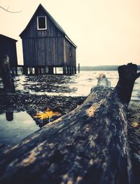 Wooden house by sea against clear sky
