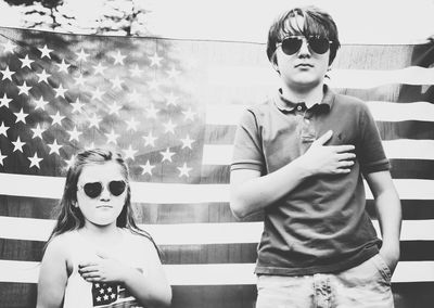 Sibling standing against american flag