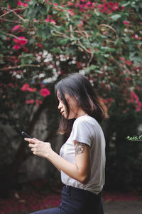 Side view of young woman using mobile phone