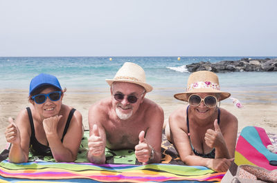 Portrait of friends on beach against sky