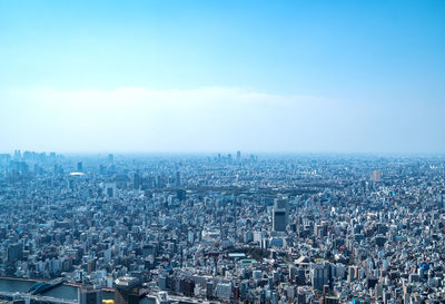 High angle view of crowd by buildings against blue sky