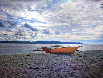 Boat moored on beach against sky