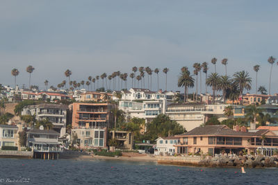 Buildings by river against sky