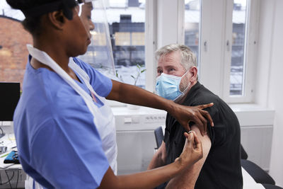 Female doctor vaccinating senior patient