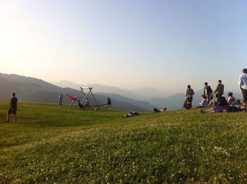 People on grassy field against clear sky
