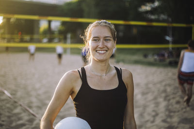 Smiling woman looking away while holding volleyball