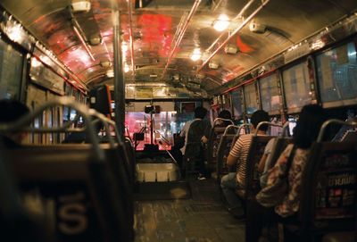 People in illuminated bus at night