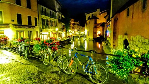 Bicycle parked by canal in city at night