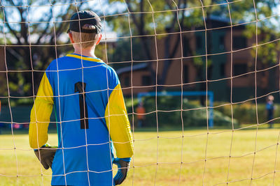 Rear view of man standing on soccer field